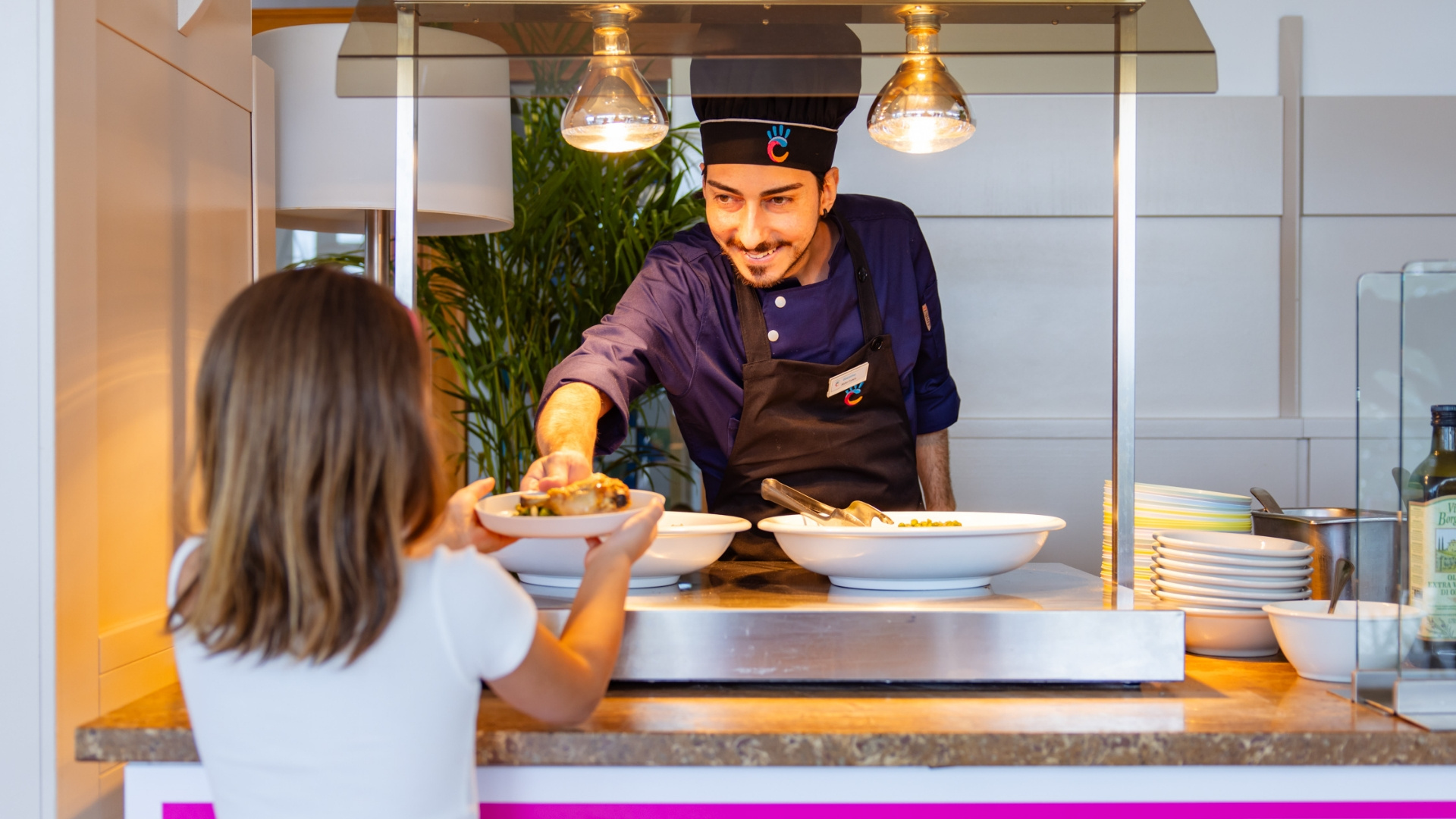 Chef serve un piatto a una bambina in un ristorante self-service.