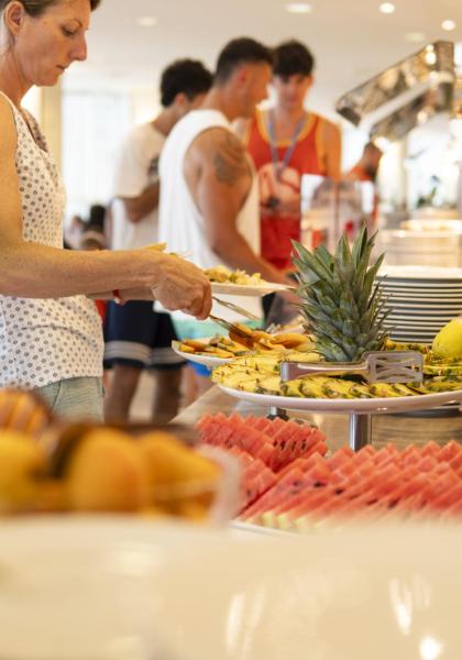 Buffet di frutta fresca con persone che si servono.