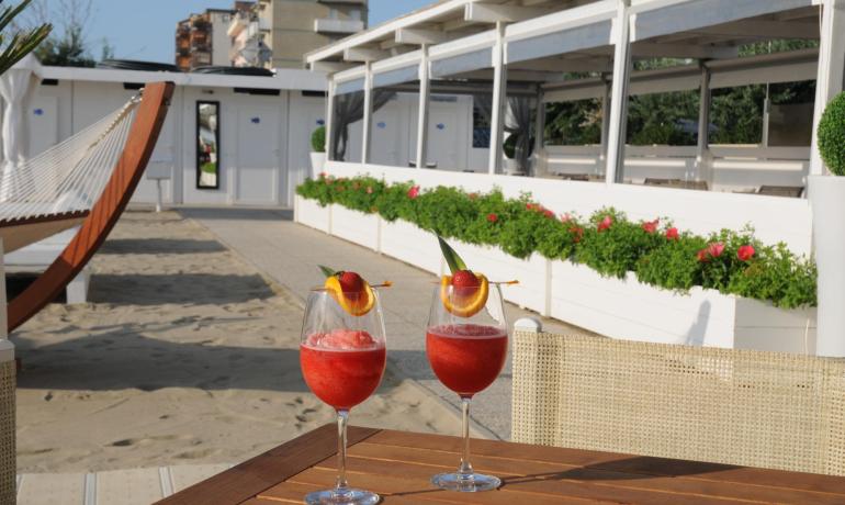 Due cocktail rossi su un tavolo in spiaggia, accanto a un'amaca.