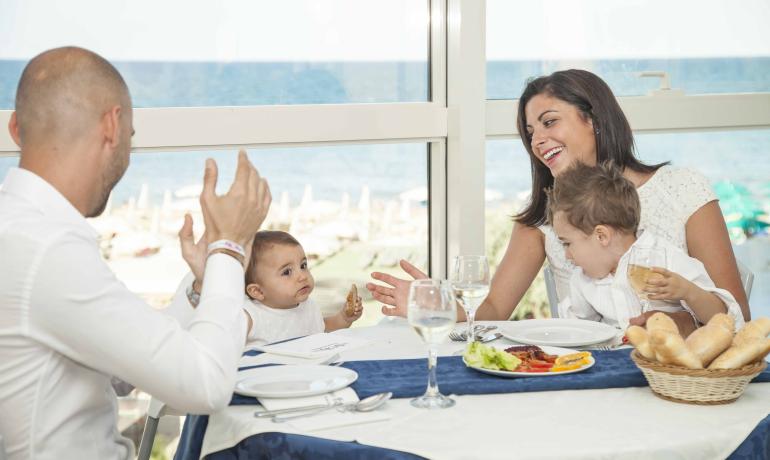 Famiglia felice che pranza insieme con vista mare.