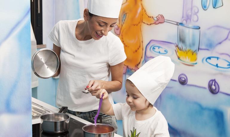 Donna e bambino cucinano insieme con cappelli da chef.