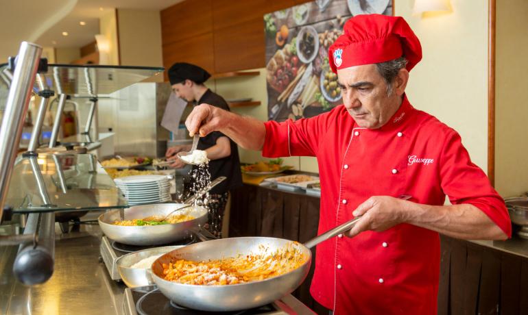 Chef cooking pasta with cheese in the kitchen.