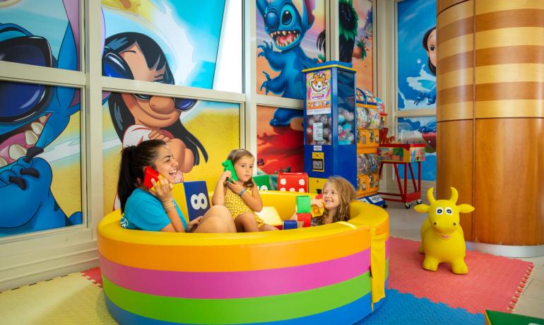 Bambini giocano in una stanza colorata con personaggi animati.