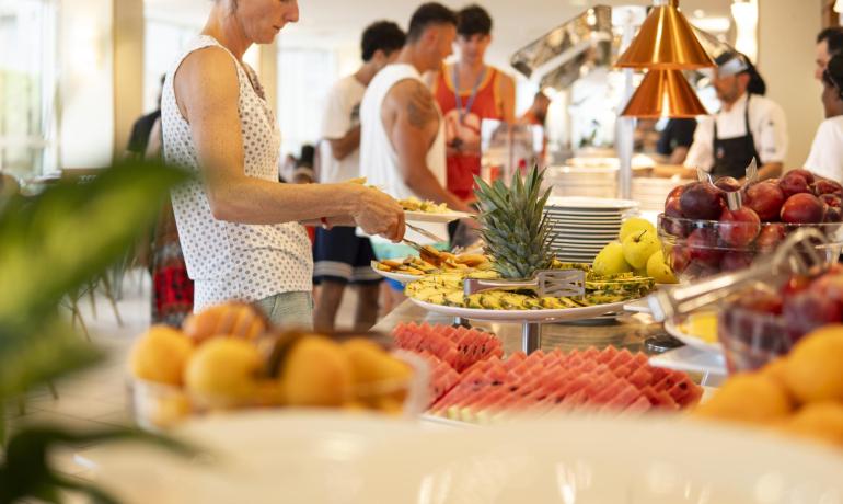 Buffet di frutta fresca con persone che si servono.