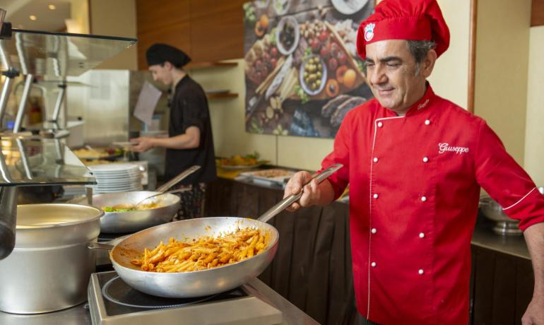 Chef cucina pasta in una cucina professionale.