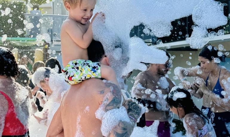 Bambini giocano in una festa di schiuma all'aperto.