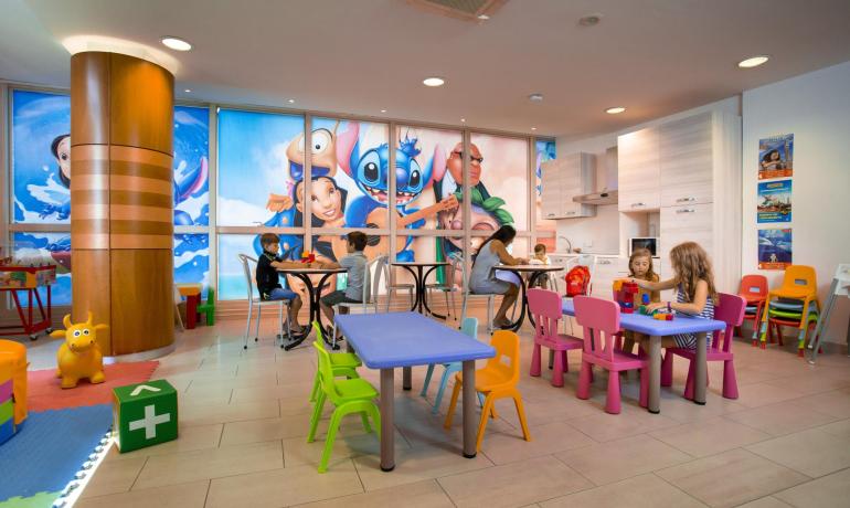 Area giochi per bambini con tavoli colorati e decorazioni vivaci.