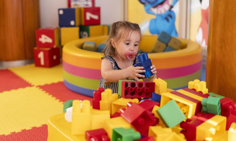 Bambina gioca con mattoncini colorati in un'area giochi.