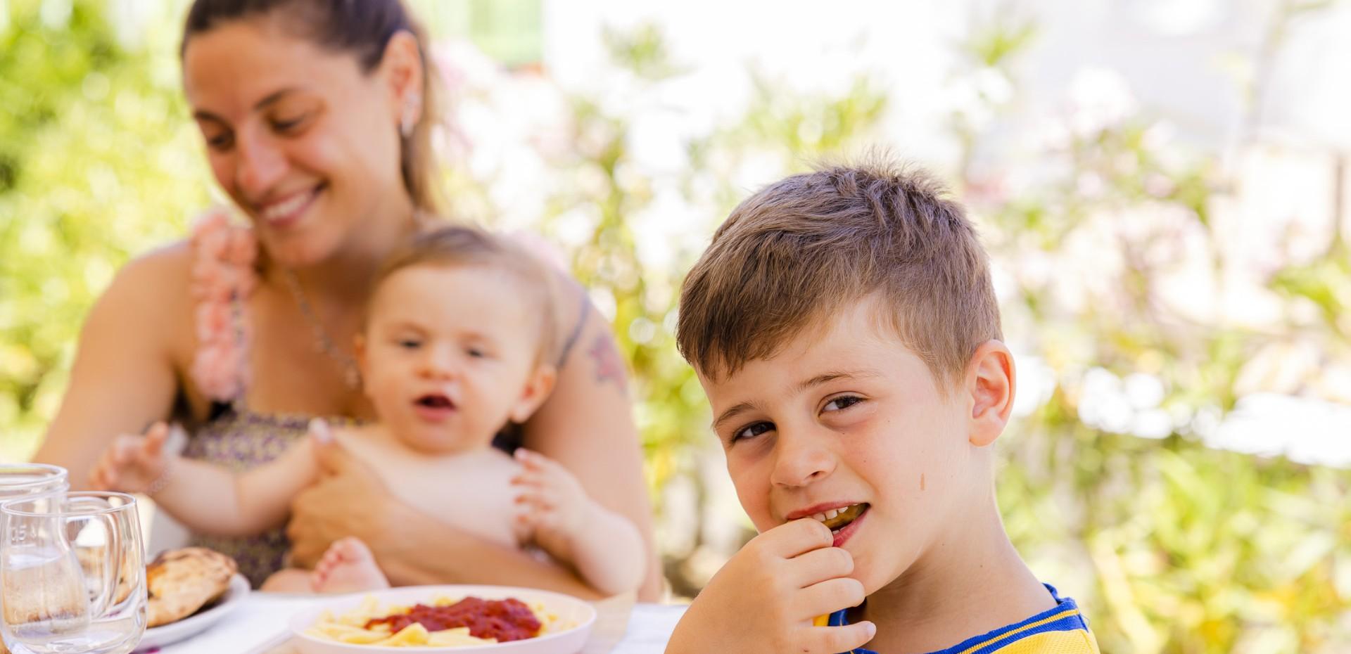 Famiglia felice mangia insieme all'aperto in una giornata di sole.