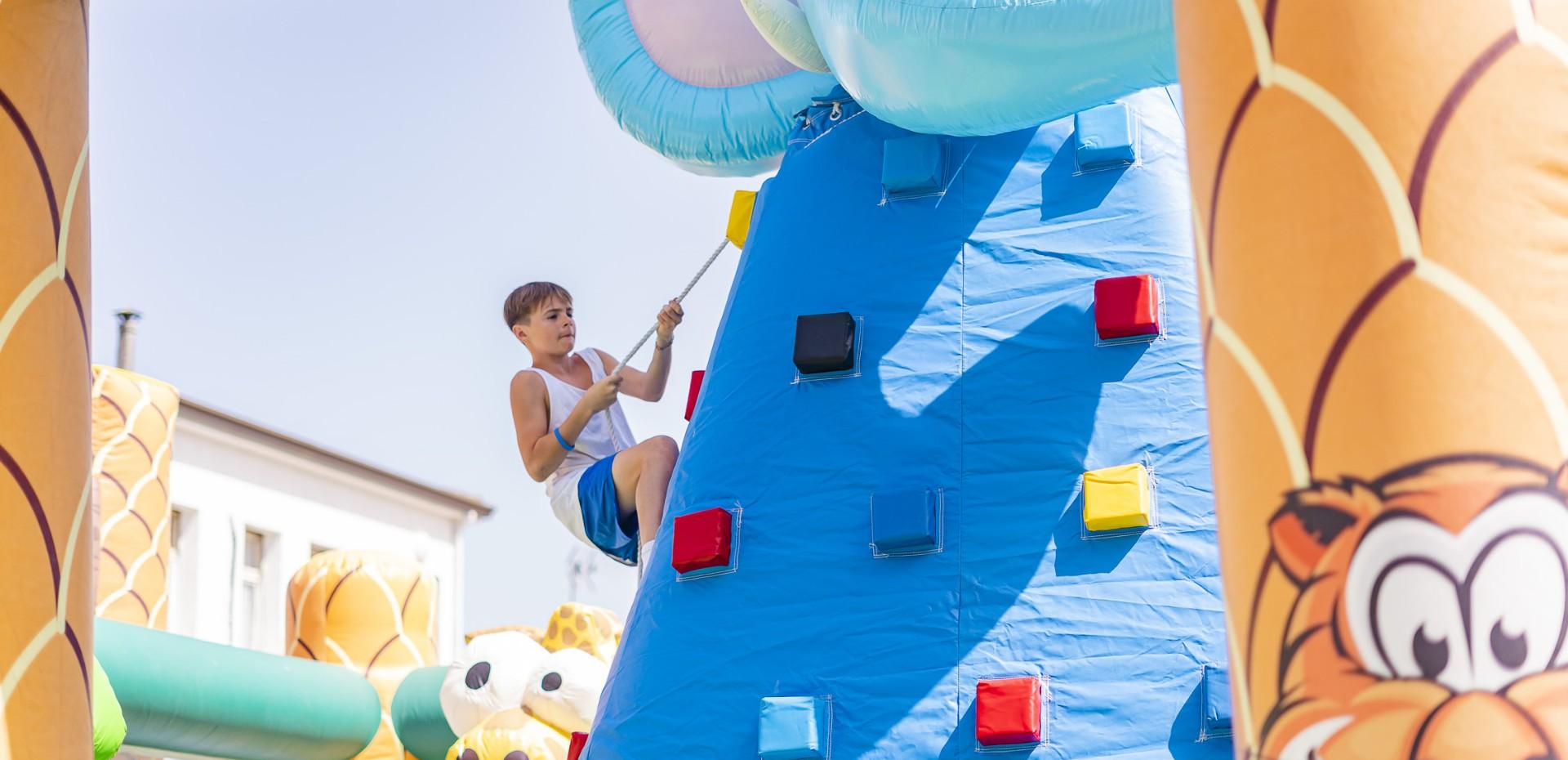 Bambino arrampica su parete gonfiabile colorata in un parco giochi.