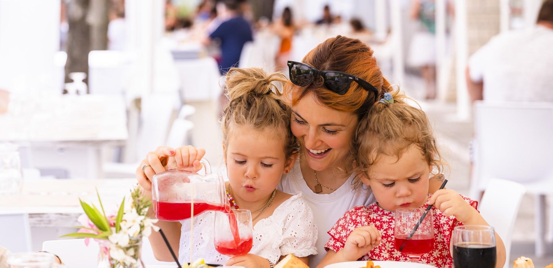Madre e figlie sorridono mentre bevono insieme al ristorante.