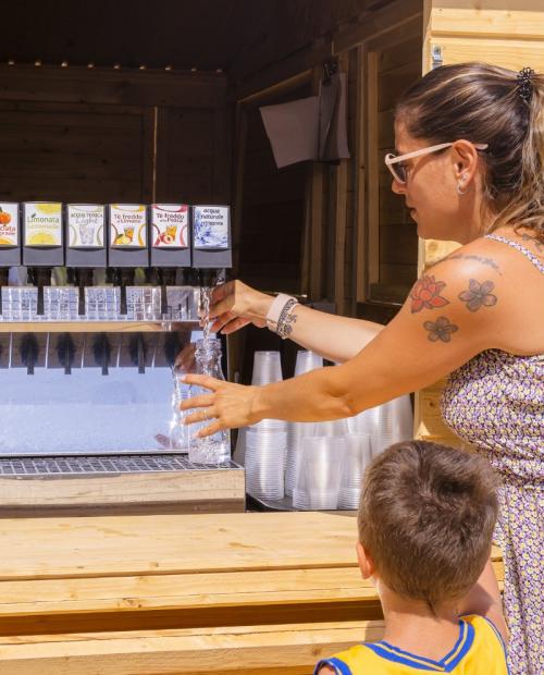 Donna riempie bottiglia d'acqua a un distributore automatico.
