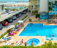 Piscina azzurra e rilassante, circondata da lettini e ombrelloni sotto un cielo sereno.