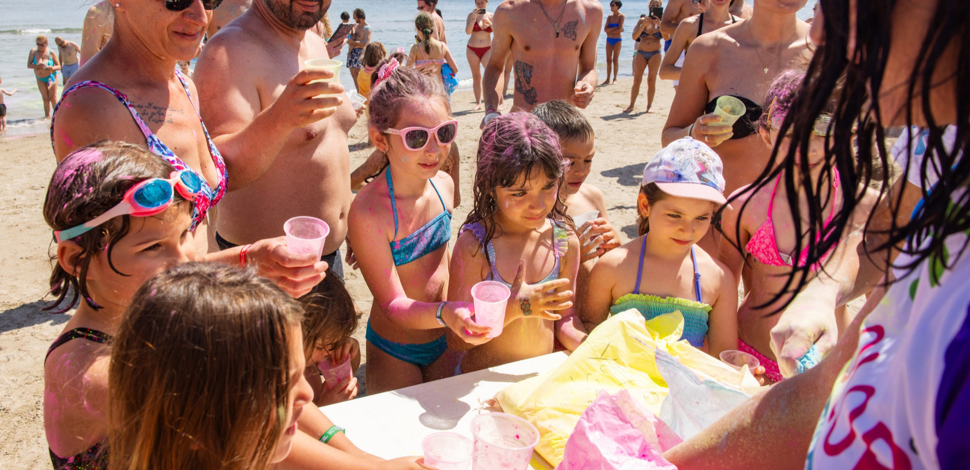 Bambini felici colorati giocano in spiaggia, sole e risate.