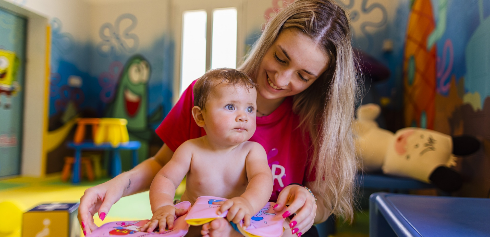 Bambino felice con educatrice, colori vivaci e atmosfera gioiosa.