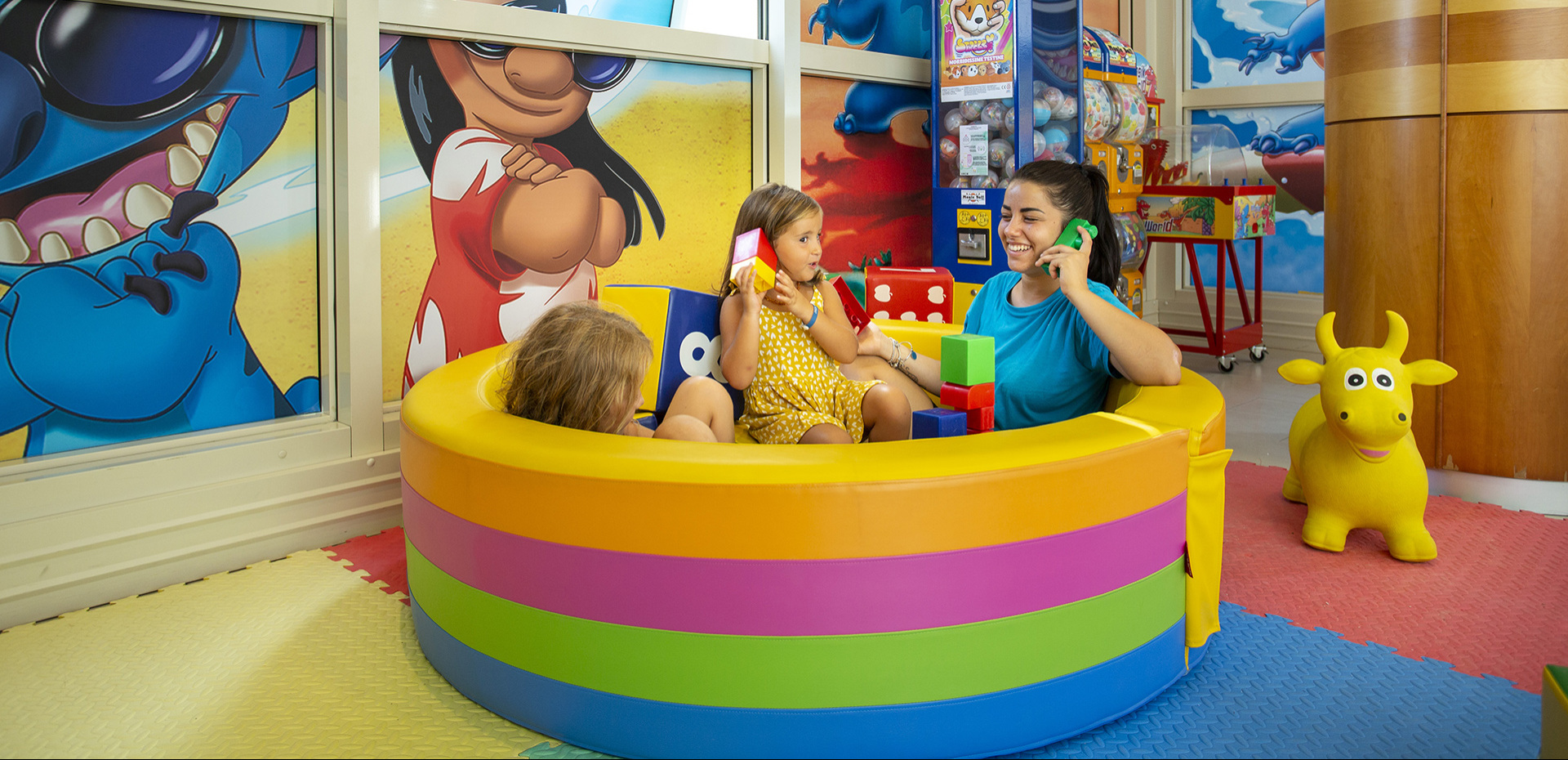 Bambina interagisce con schermo colorato, gioco educativo con animali e sfondo marino.