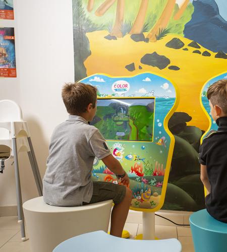 Sala giochi con supereroi, TV e arredi colorati per bambini.