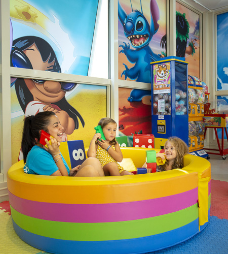 Bambina e donna giocano insieme su un tappeto colorato con giocattoli educativi.