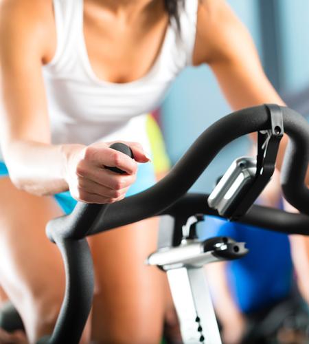 Donna energica pedala su cyclette in palestra, atmosfera di determinazione e vitalità.