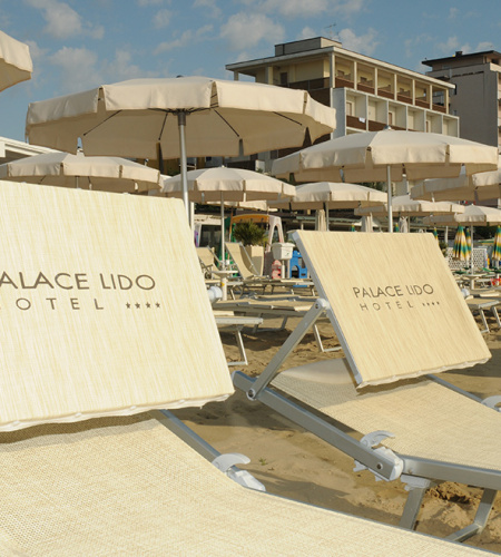 Plage ensoleillée avec transats élégants, parasols et un hôtel en arrière-plan.