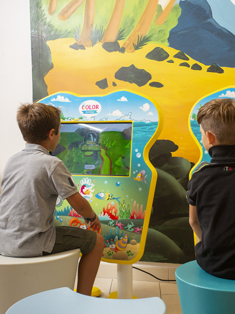 Sala giochi con supereroi, TV e arredi colorati per bambini.