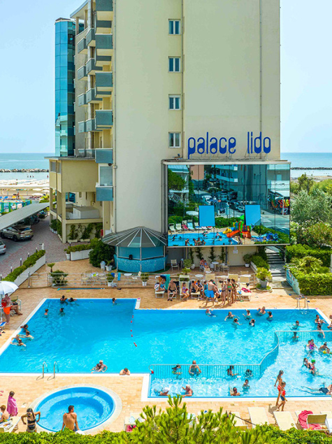Hôtel animé avec piscine et vue sur la mer, ambiance estivale joyeuse.
