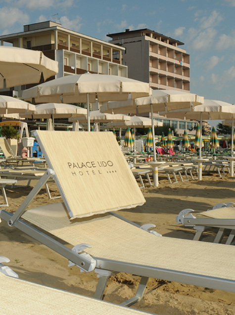 Plage ensoleillée avec transats élégants, parasols et un hôtel en arrière-plan.