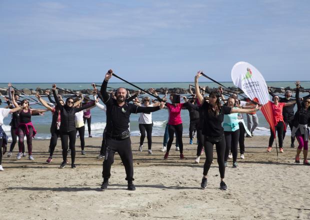 Group fitness class on the beach with resistance bands.