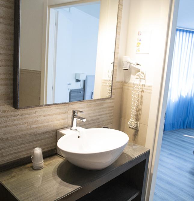 Bagno moderno, luminoso, accogliente; camera da letto con tende blu, atmosfera rilassante.