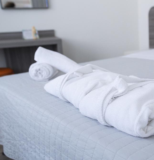 Accappatoio bianco su letto ordinato, atmosfera di relax e comfort.