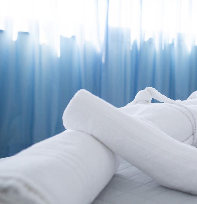 Accappatoio bianco su letto, luce soffusa e atmosfera rilassante.