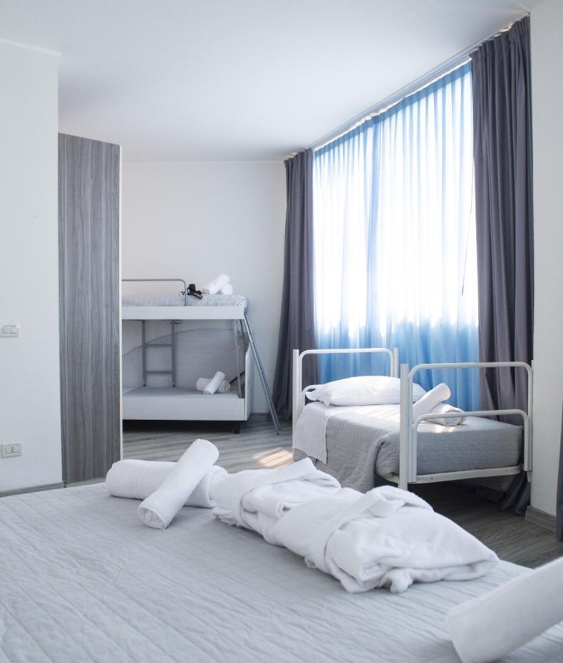 Bambina salta sul letto, mentre una donna incinta la osserva sorridendo.